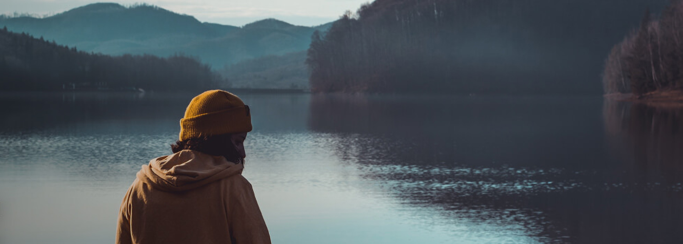 Woman admiring a lake surrounded by mountains