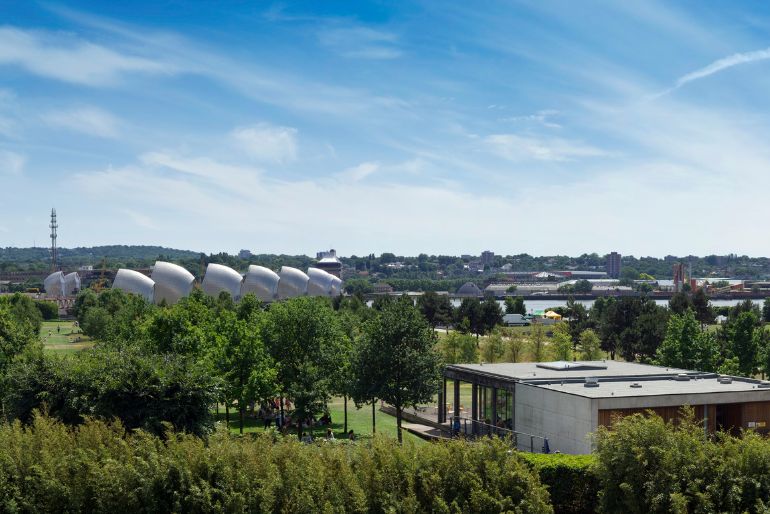 A scenic view of a lush valley with distinctive dome structures in the distance under a clear blue sky.